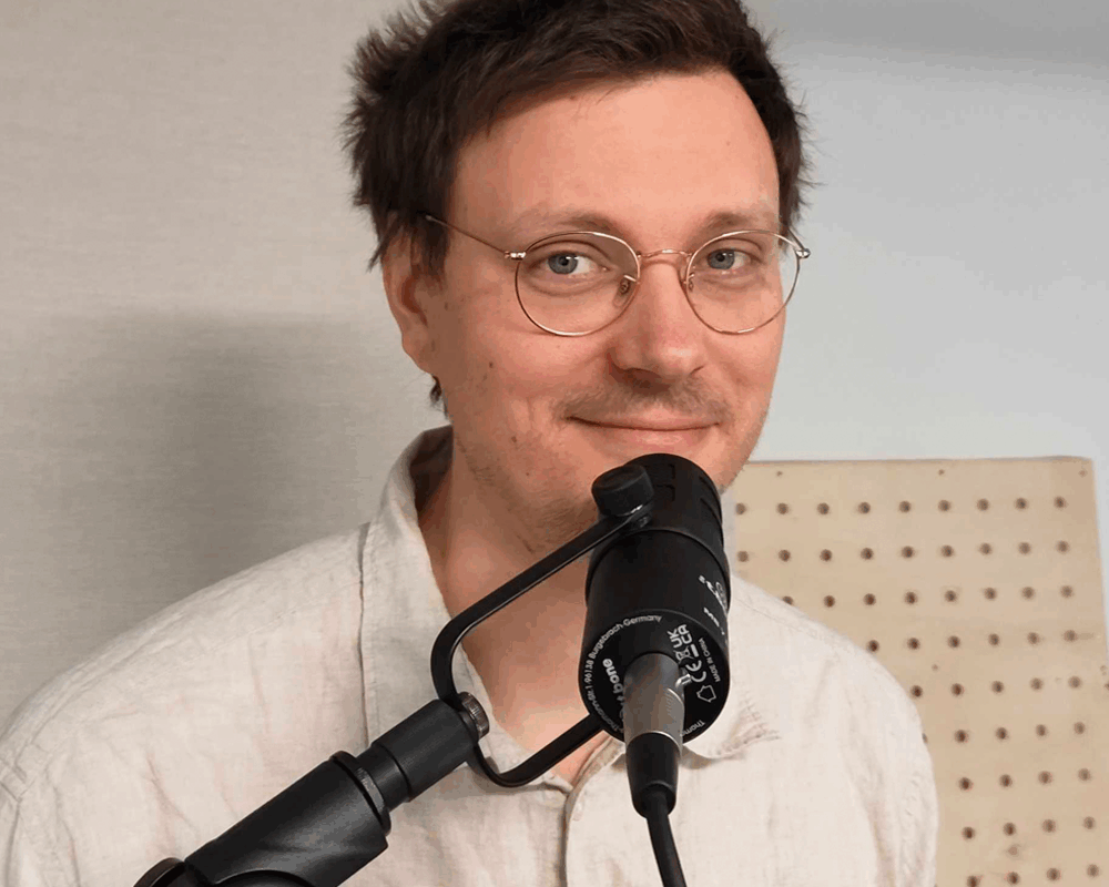 Foto von Nils Sommer vor einem Podcastmikrofon